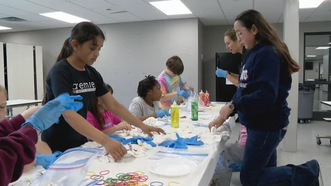 Premier Arts Academy students gather around a table to tie-dye tee-shirts. The school integrates arts into its everyday curriculum. (WSBT Photo)